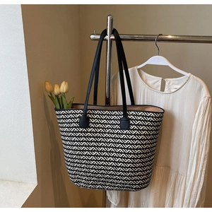 Detail of woven tote bag with black and white wave pattern and black leather handles