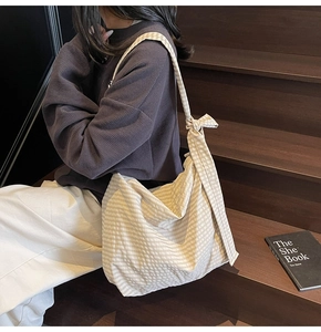 Detail of cream plaid tote bag featuring decorative shoulder knots and soft fabric texture