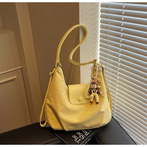 Detail of yellow nylon tote bag with texture, flap closure and decorative pearl charm