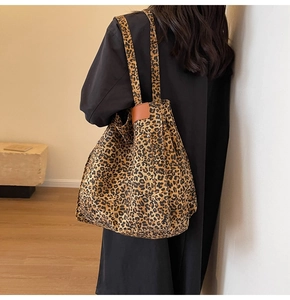Macro shot of large leopard print tote bag detailing brown leather accents and rivets