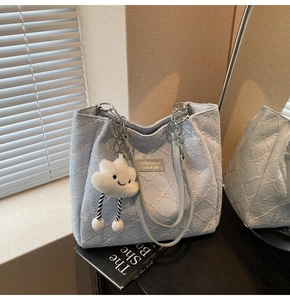 Close-up of blue floral tote with silver chain strap and a white cloud plush charm