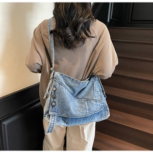 Detail of vintage blue denim tote with metallic button accents and textured wash finish