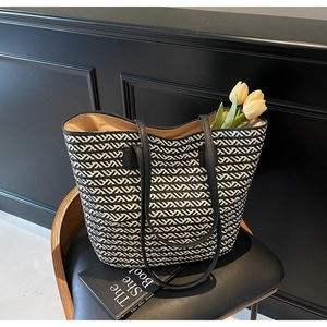 Detail of black and white chevron woven tote bag with premium leather straps on a chair