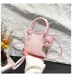 Détail du mini sac seau en cuir grainé rose avec breloque cœur argentée et lanière