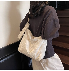 Detail of white quilted tote bag with textured fabric worn on the shoulder for commuting