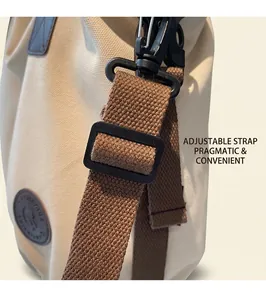 Detail of adjustable dark brown woven strap with matte black buckle on beige canvas bag
