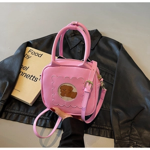 Detail of pink glossy patent leather bag featuring cartoon bear circular window
