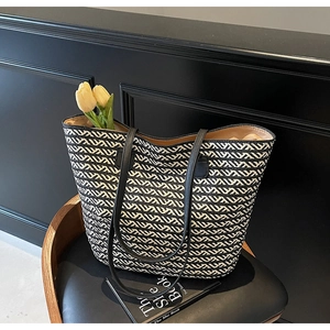 Detail of black and white woven tote bag with wavy patterns and slim shoulder straps