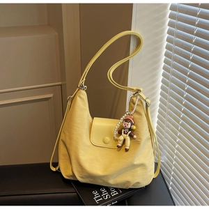 Detail of soft yellow nylon hobo shoulder bag with a cute pearl doll pendant accessory
