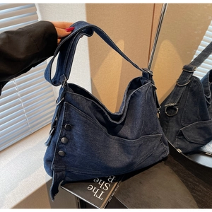 Detail view of denim tote bag with metallic buttons and wide shoulder strap