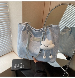 Detail view of light blue floral tote bag with silver chain and plush cloud charm accessory