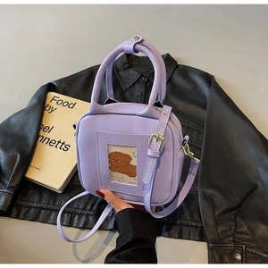Detail of purple patent square handbag with dog card and golden hardware hardware