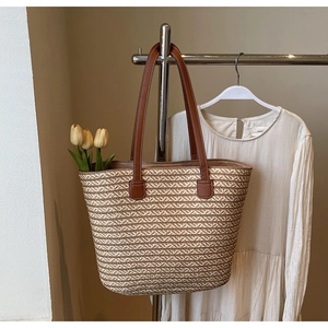 Detail of herringbone weave straw tote bag with brown leather handles and tulip decoration