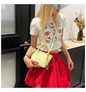 Detail view of yellow mini tote bag with lychee texture and silver heart pendant charm