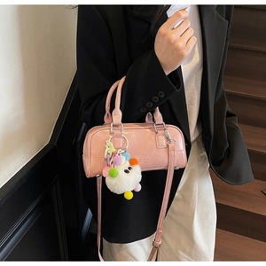 Pink glossy bowling bag with a colorful plush keychain on a professional model