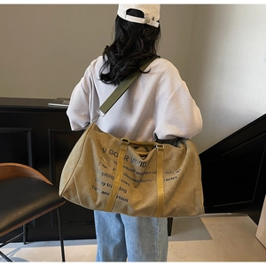Model wearing a large khaki canvas travel tote bag with vintage VIGOR VIVID branding