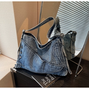 Close-up of washed blue denim tote bag with metal button pocket and adjustable strap