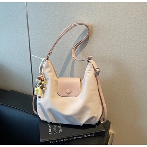 Close-up of pink nylon shoulder bag with adjustable strap and cute cartoon charm