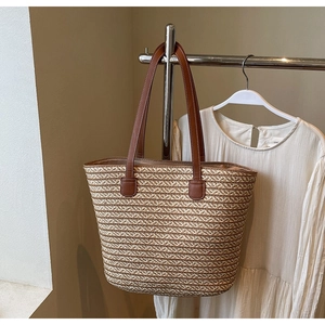 Detail of woven straw tote bag texture with brown leather handles on a hanger