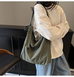 Detail of dark green plaid tote bag featuring a decorative bow tie on the soft shoulder strap