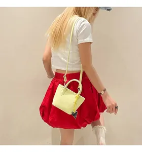 Détail du sac seau en cuir grainé jaune clair avec pendentif en forme de cœur noir