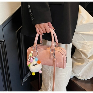 Close-up of pink faux leather bowling bag with cute white plush heart charm
