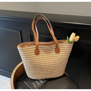 Detailed close-up of beige straw woven tote bag featuring brown leather strap and tulip decor