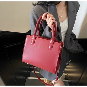Close-up of red leather tote bag with golden lettering and detachable shoulder strap
