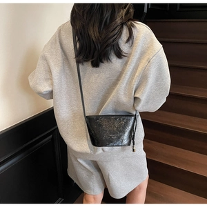 Détail du sac seau noir brillant avec texte Fashion Paris porté par un mannequin ici