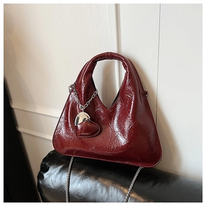Detail of burgundy ruched dumpling bag with silver chain and fashion logo engraving