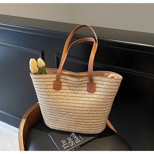 Detailed close-up of the woven straw tote bag texture and reinforced leather handles