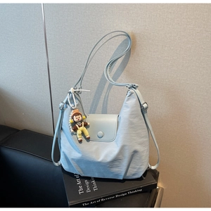 Detail of light blue hobo bag with adjustable strap and cute cartoon doll pendant