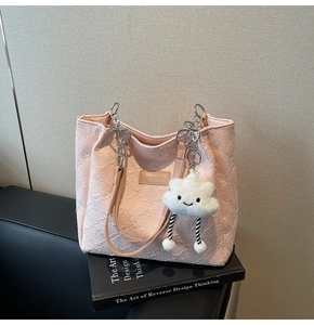 Detail of pink tote bag with floral embossing and a white cloud plush charm