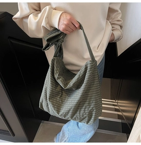 Green checkered canvas tote bag with shoulder strap knot detail shown on person