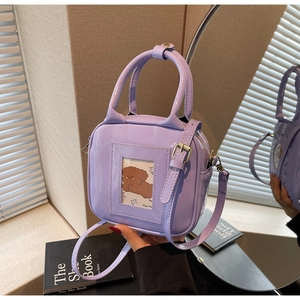 Detail of lavender patent leather crossbody bag with transparent dog-pattern card slot