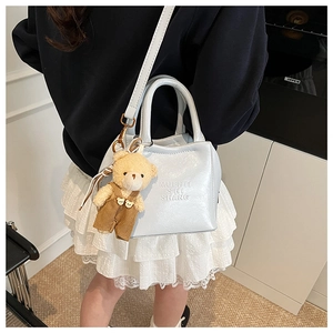 Detailed view of light blue leather crossbody bag with teddy bear charm on model