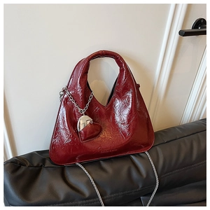 Close-up of shiny burgundy dumpling bag with silver chain and heart charm detail