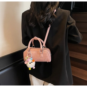 Back view of model wearing a pink bowling bag with a white plush doll charm