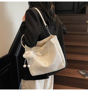Detail of cream tote bag featuring embossed 3D floral texture and plush cloud charm