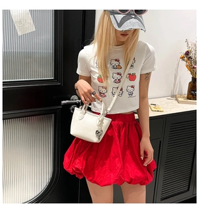 Gros plan du sac seau en cuir grainé blanc avec pendentif cœur porté par un mannequin