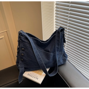 Detail of dark blue denim tote bag with metal buttons and wide shoulder strap