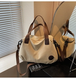 Detailed macro view of beige canvas tote with brown webbing handle and round logo tag