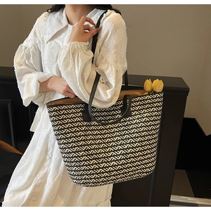 Detail of a large woven tote bag with black and white V-shaped patterns and leather straps