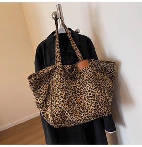 Detail of leopard print canvas tote bag featuring a leather patch and reinforced rivets