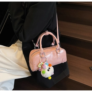 Pink glossy bowling bag with plush charm shown in a stylish lifestyle fashion setting