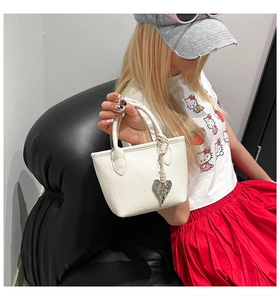 Détail du sac seau blanc en cuir grainé avec breloque cœur argentée sur mannequin