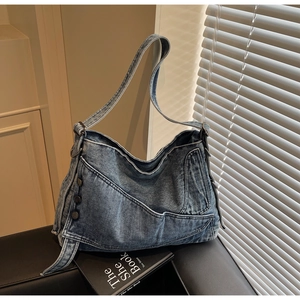 Detailed view of wash blue denim hobo bag with vintage metal button and stitching details