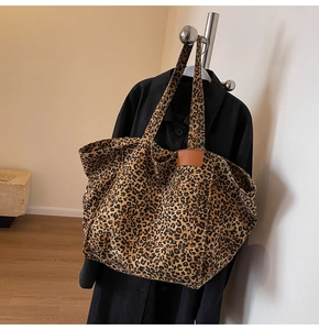 Detail of leopard print tote bag featuring leather patchwork and metal rivet reinforcement