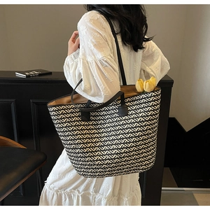 Close-up of woven tote bag with black and white wavy patterns on a model shoulder