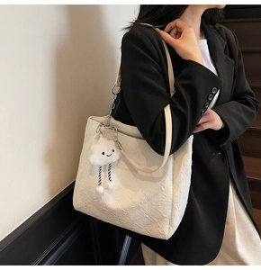 Detail of white embossed tote bag featuring a cute plush cloud charm and dual straps